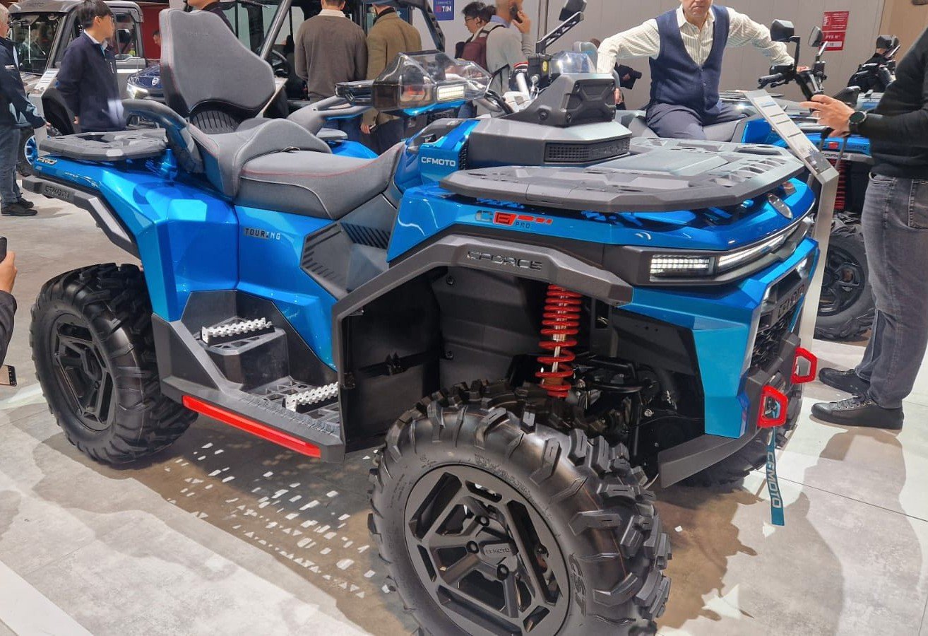 Metallic-blue CFMoto CForce single-seat quad ATV with black wheels displayed at an indoor show