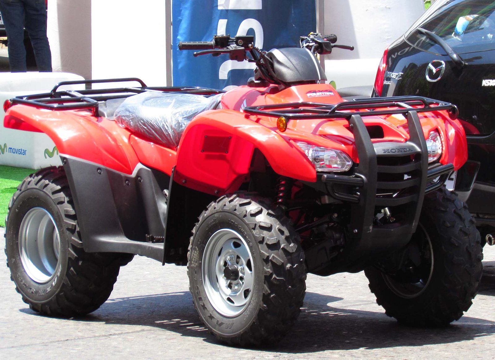 Red Honda TRX 420 utility ATV (four-wheel quad) with front brush guard and cargo rack, parked outdoors