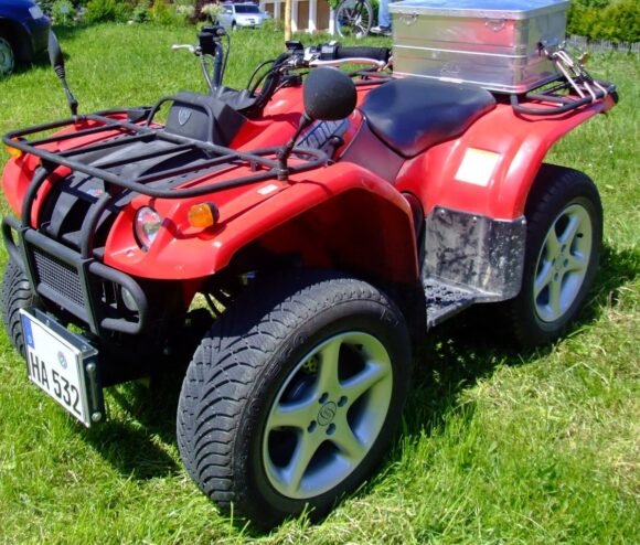 Red Yamaha Kodiak utility ATV with a rear top case on grass