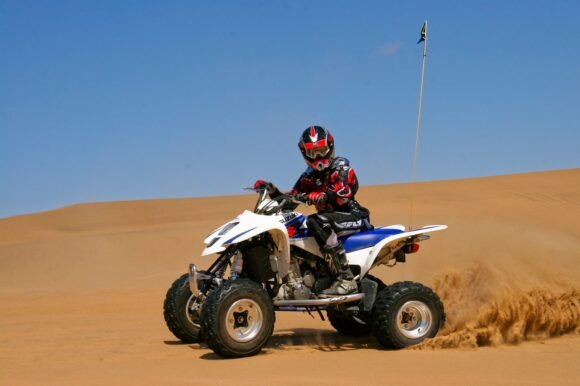 Rider on a Suzuki QuadSport Z400 sport ATV jumping over a sand dune