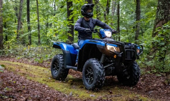 Blue Honda Rubicon ATV riding on a forest trail