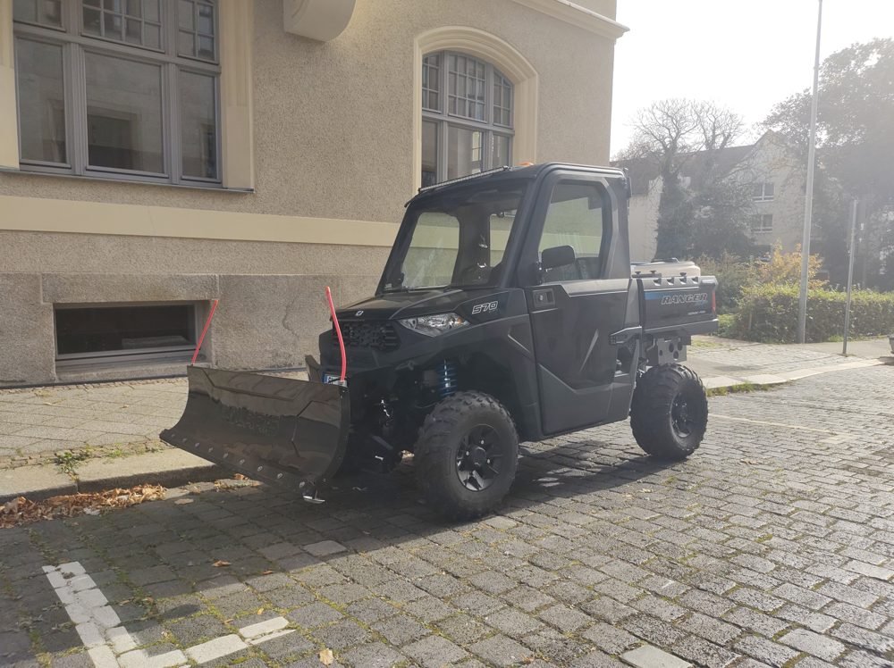 Polaris Ranger 570 fitted with a front snow plow, parked on a residential street