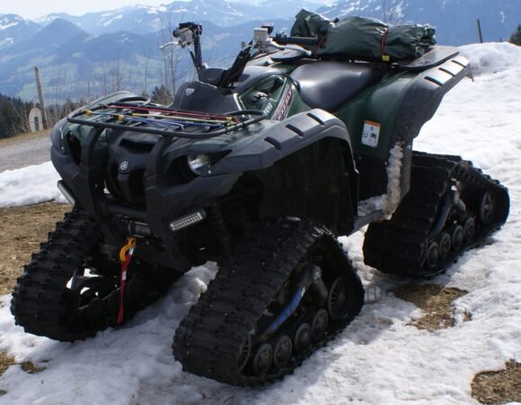 Yamaha Grizzly 700 ATV fitted with aftermarket snow tracks in an alpine setting, same 686cc Ultramatic platform as the Kodiak 700